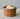 Terracotta Faisselle container with garlic and an onion on a neutral background