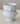 A pair of stacked white ceramic bowls with sculptural lion head handles and a flared pedestal base, photographed against a soft neutral background.