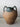 Vintage ceramic jar with green top and brown body on a light gray surface.