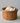 Terracotta Faisselle container with garlic and an onion on a neutral background