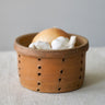 Terracotta Faisselle container with garlic and an onion on a neutral background