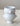 A pair of stacked white ceramic cups with sculpted animal head handles, set on a textured beige fabric surface against a neutral gray background.