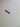 Close-up of a white ceramic surface with a small dark blue painted mark and faint embossed characters.