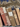 Stack of old, worn books with visible wear and tear on a patterned fabric background