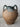 Vintage terracotta vase with green handles on a light gray surface.